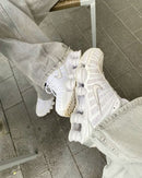 Nike Shox TL Sail aan een touw gehangen, gefotografeerd tegen grijze muur met zicht op reflecterende details en lichte kleurtonen