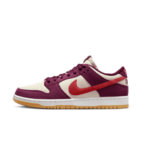 Zijaanzicht van de Skate Like a Girl x Nike SB Dunk Low Barely Rose DX4589-600 met roze suède upper, rode swoosh en geborduurde details