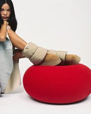 Model zittend op rode poef met de UGG Dipper Puffer aan, combinatie van pufferstof en suède zichtbaar in zachte studioverlichting