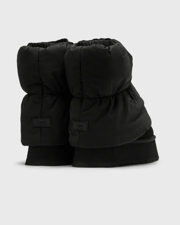 Flatlay van beide zwarte UGG Dipper Puffer boots op witte ondergrond, met zicht op de gewatteerde schacht en chunky zool