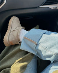 UGG Driftwood Ultra Mini op wit beddengoed, zachte pantoffelachtige uitstraling voor binnen en buiten