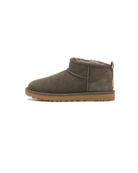 Zijaanzicht van de UGG Classic Ultra Mini Boot in de kleur slate, uitgevoerd in zacht grijs suède met het kenmerkende lage silhouet en comfortabele shearling binnenvoering