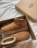 Close-up van UGG Ultra Mini Chestnut op wit beddengoed, sfeervol beeld met zachte winteruitstraling