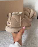 UGG Ultra Mini in driftwood gedragen binnenshuis op een bank, cozy styling met winterse sfeer