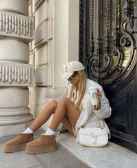 Lifestyle moment op traptrede voor een sierlijk gebouw met de UGG Platform in Chestnut gecombineerd met casual streetwear