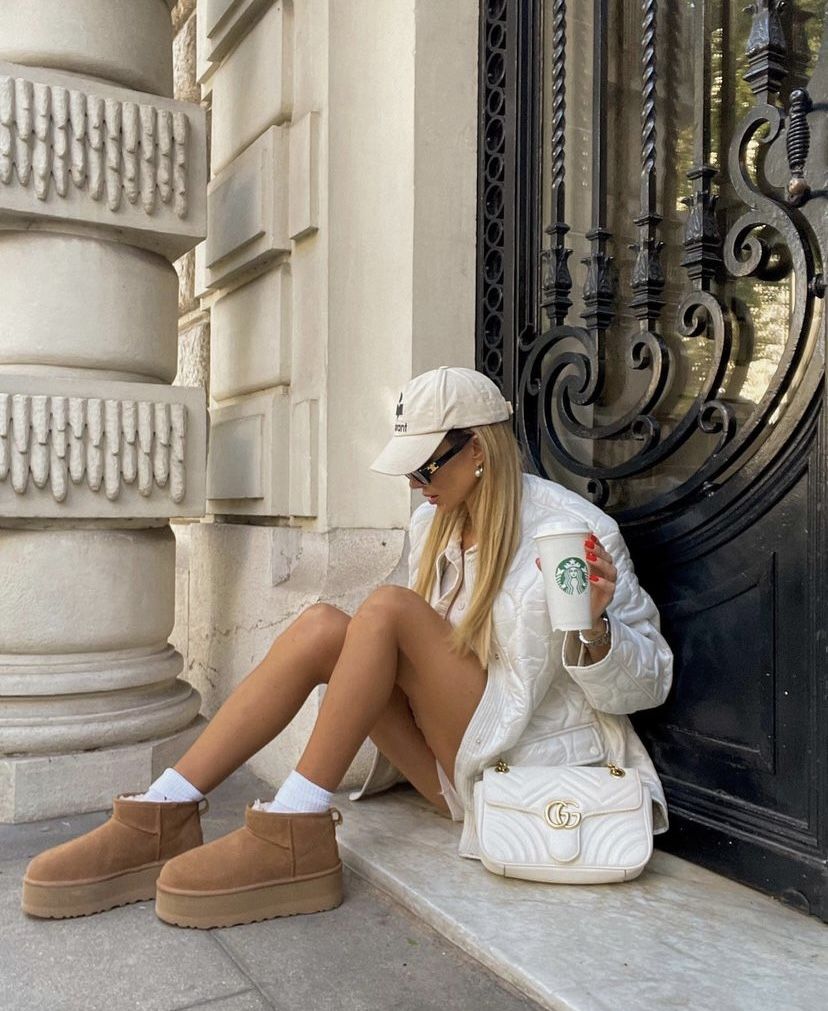 On-feet shot van beige UGG platform boots gedragen met witte sokken op een marmeren traptrede, urban maar cozy vibe