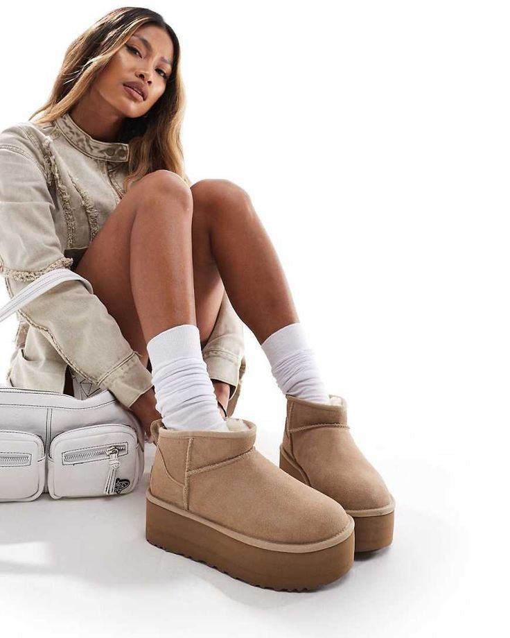 Cozy zitmoment in zachte stoel met UGG Ultra Mini Platform in zand, gecombineerd met witte sokken en oversized trui