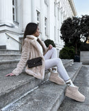 Lifestyle opname van model op marmeren trappen met beige trenchcoat en UGG Classic Seal aan, gefotografeerd in stedelijke omgeving