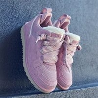 Flatlay van twee Dusty Orchid sneakers op trap gestyled met daglicht vanuit links, veters en sheepskin detail zichtbaar