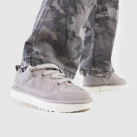 On-foot beeld van model in camouflagebroek met UGG Campfire aan, gefotografeerd in studio met witte vloer en daglicht