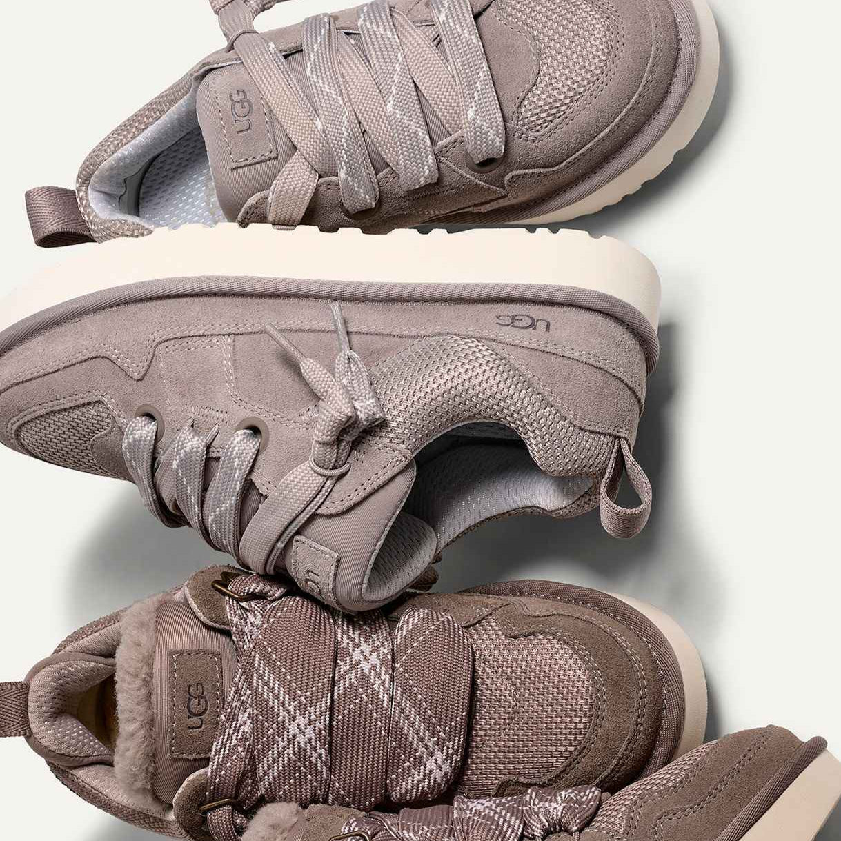 Flatlay van gestapelde UGG Campfire sneakers, met zicht op suède structuur, lichtgrijze zool en subtiel logo bij de hiel