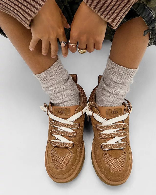 Bovenaanzicht van gedragen UGG Lowmel Lo Chestnut met witte sokken, model zittend met voeten naast elkaar op beige vloer