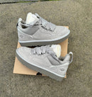 Beide sneakers naast elkaar op zacht tapijt met lichtinval van bovenaf, benadrukt de kleur en textuur van het suède