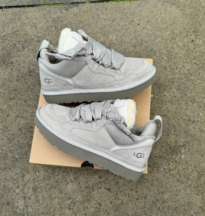 Beide sneakers naast elkaar op zacht tapijt met lichtinval van bovenaf, benadrukt de kleur en textuur van het suède