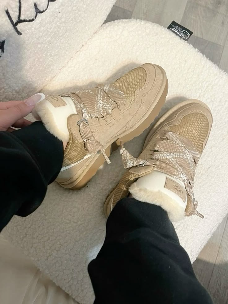 Kindervoeten in de beige Lowmel Sand sneakers, gecombineerd met zwarte joggers en witte vloer in ochtendlicht