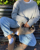 Lifestylebeeld van UGG Tasman in Chestnut gecombineerd met blauwe jeans en oversized gebreide trui op bankje