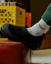 Lifestylebeeld met sokken in de zwarte Tasman Weather, zittend op rode bank met vintage vibe en industriële vloer