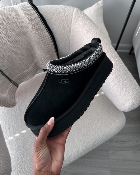 Close-up van UGG Tazz Slipper Black 1122553-BLK in hand, met zichtbare suède textuur, heritage braid afwerking en stevige platformzool, gefotografeerd door Snrkickz.