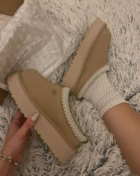 UGG Tazz Slipper Sand 1122553-SND gedragen in huiselijke setting, beige suède gecombineerd met cozy sokken, vastgelegd in natuurlijke belichting door Snrkickz.