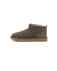 Zijaanzicht van de UGG Classic Ultra Mini Boot in de kleur slate, uitgevoerd in zacht grijs suède met het kenmerkende lage silhouet en comfortabele shearling binnenvoering