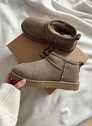 Close-up van UGG Ultra Mini Antilope op wit beddengoed, cozy en minimalistische sfeer